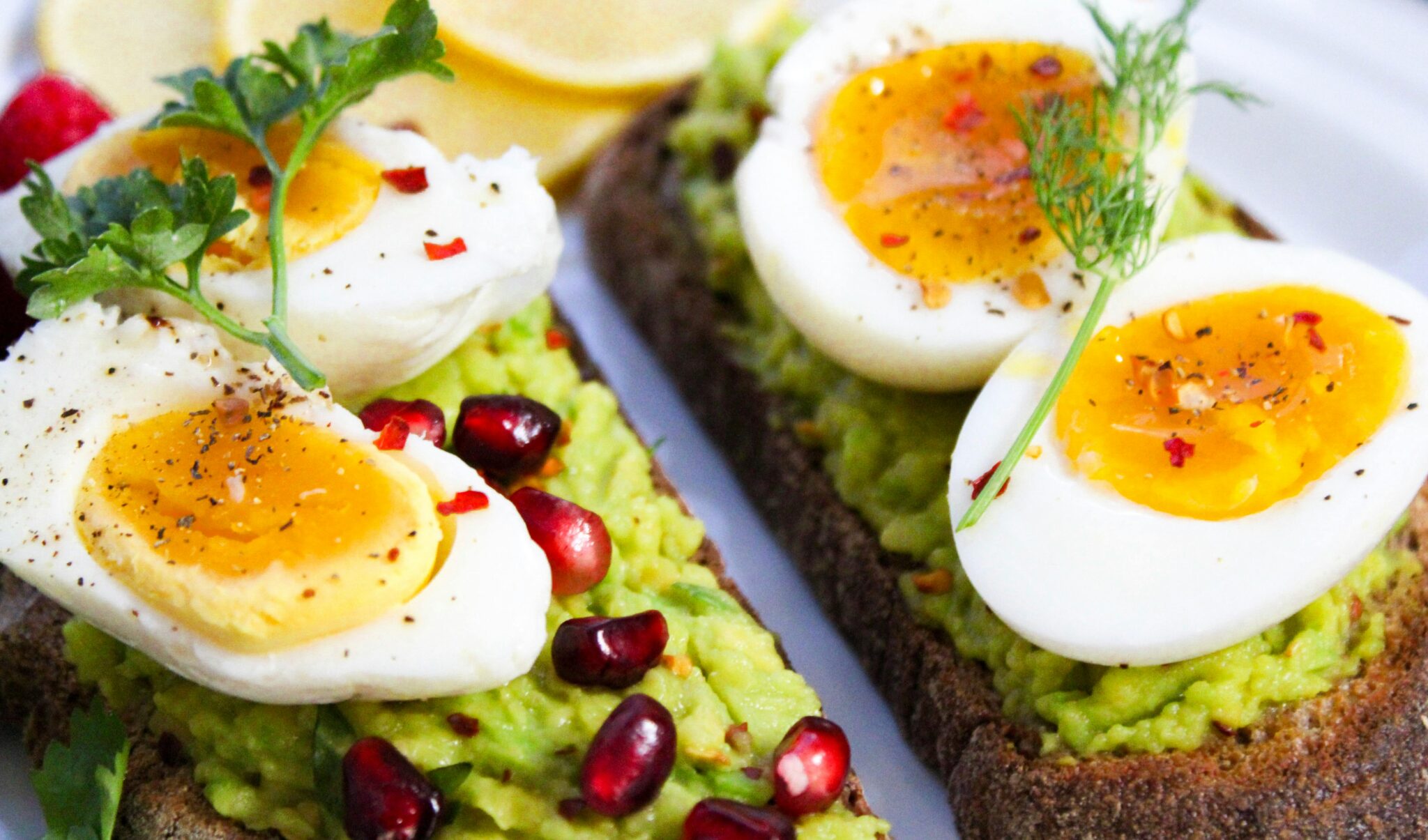 Savor this delicious avocado toast topped with soft-boiled eggs and garnished with pomegranate seeds.